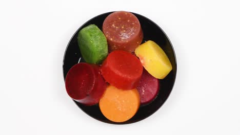 calabaza congelada, plátano, zanahoria, manzana, melocotón, fresa, morera, frambuesa y batido de kiwi en un plato blanco. plato en un fondo blanco. vista superior. movimiento de bucle. rotación 360.