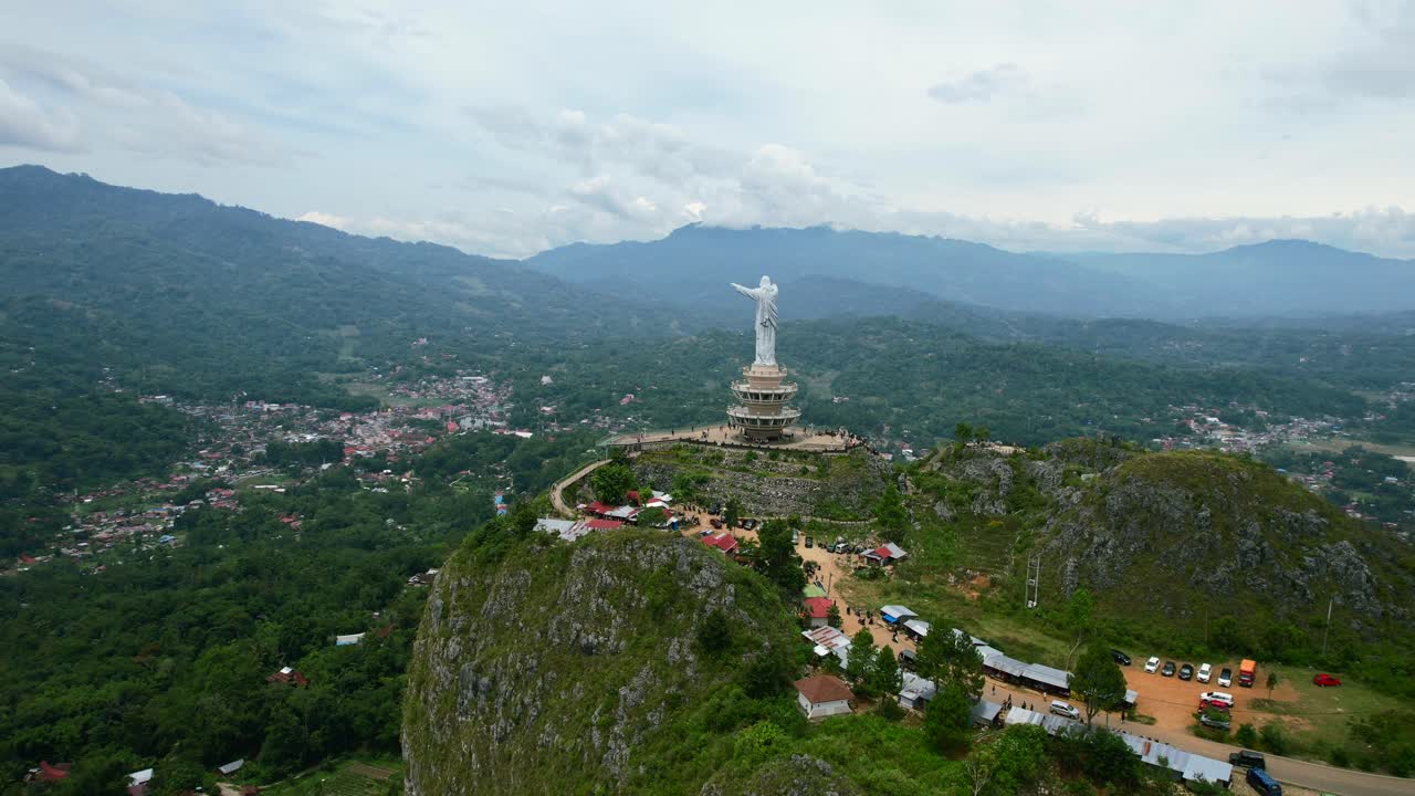Aerial of a Jesus Christ Statue in Tana Toraja Sulawesi at the top of a mountain with tourists and shops