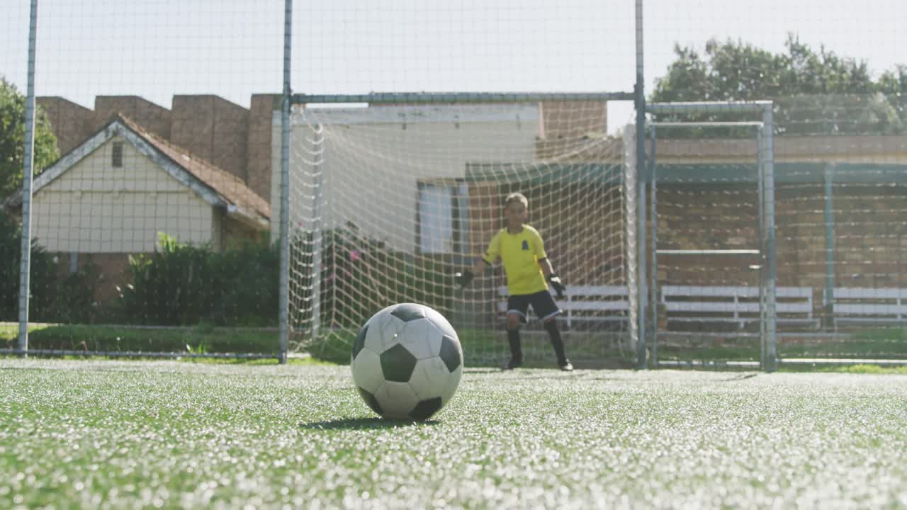 niño de fútbol afroamericano en azul marcando en un día soleado