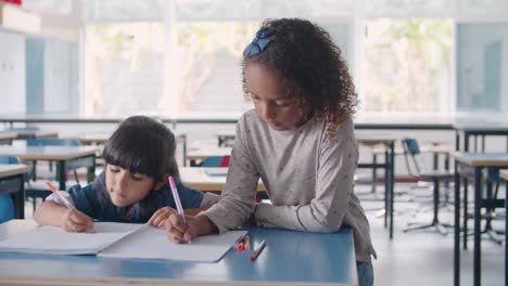 Focused-African-American-and-Latin-primary-school-pupils-doing-drawings-on-notebook