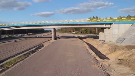 aerial fly under the new established viaduct on new highway interchange near the city