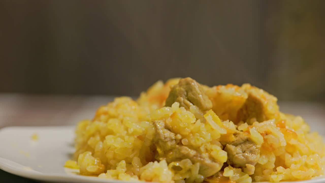 plato de pilaf caliente, pilau, pilaw o pilaf con carne de pavo girando en el plato