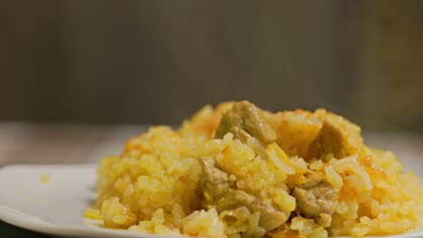 dish of hot pilaf, pilau, pilaw or pilaff with turkey meat spinning on plate