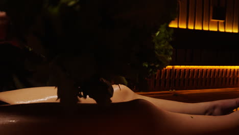 woman receiving a traditional herbal body treatment in a sauna