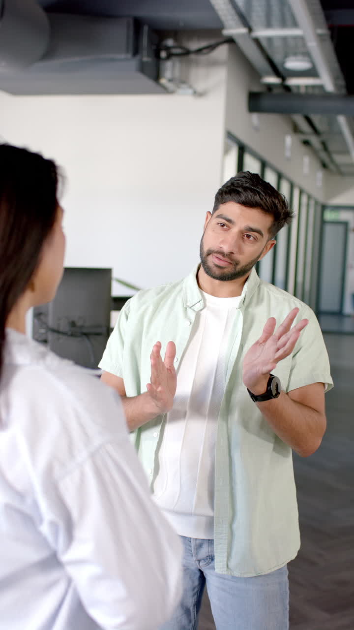 Vertical video: Discussing project details, colleagues having conversation in modern office setting