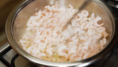 spreading small fresh shrimps with black spatula in hot pot