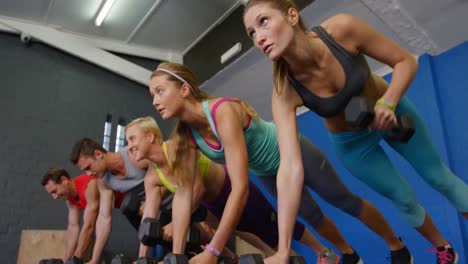 Group-of-people-performing-push-up-with-kettlebell