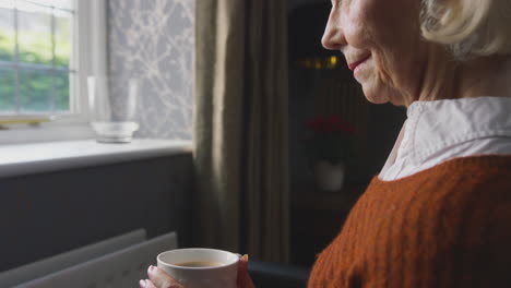 Senior-Woman-In-Wheelchair-Trying-To-Keep-Warm-By-Radiator-During-Cost-Of-Living-Energy-Crisis