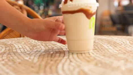 hands place iced coffee and caramel shake on a patterned table in a cozy gold coast cafe setting