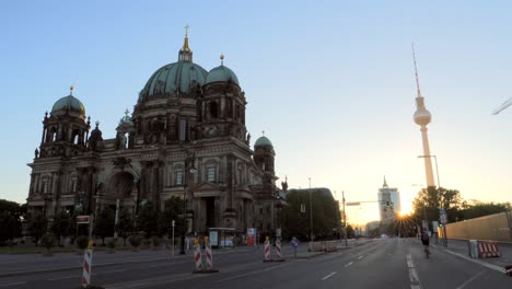 cyclist passing the berlin cathedral at sunrise