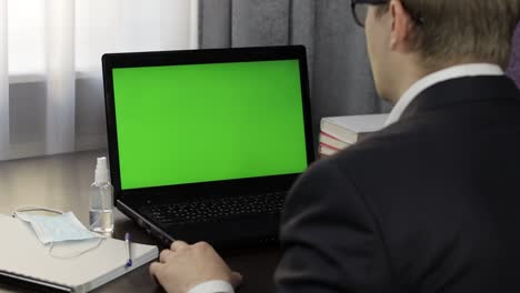 Man-have-video-call-conference-on-laptop-with-green-screen.-Distance-work-online