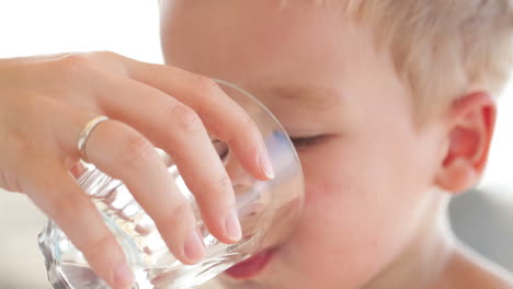 un niño bebe un vaso de agua dulce.