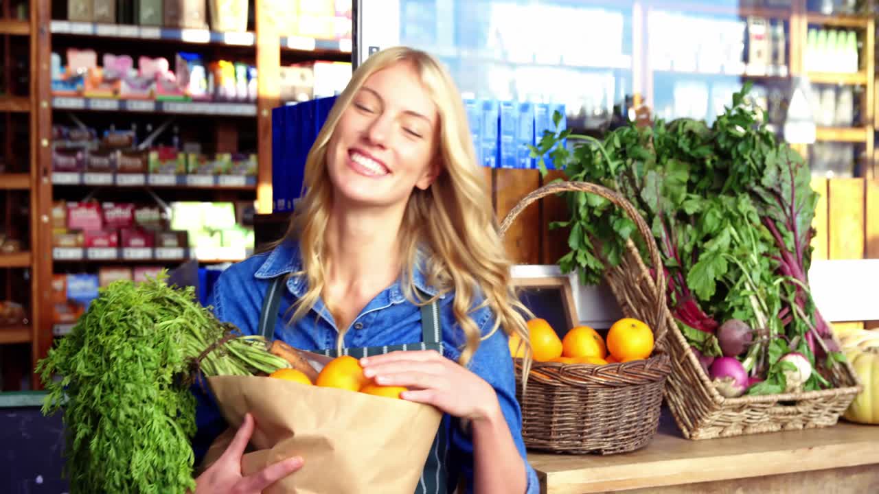 retrato de una mujer sonriente sosteniendo una bolsa de comestibles en la sección orgánica
