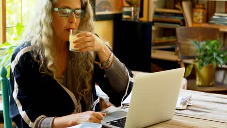 mature woman having juice while using laptop 4k