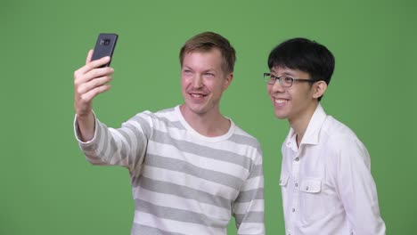 two happy young multi-ethnic businessmen smiling while taking selfie together