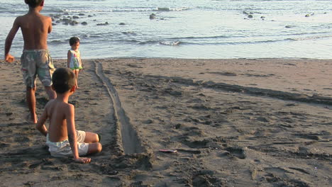 children roll bottle caps down a narrow track