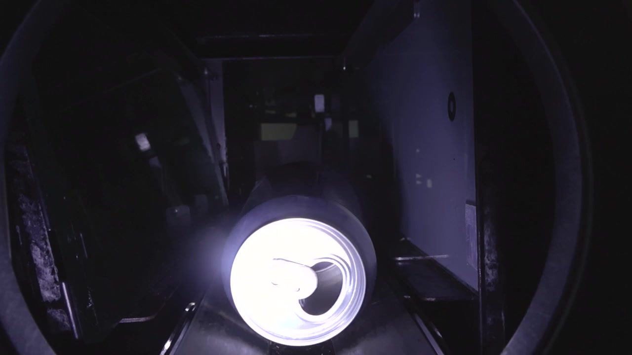 Lata de alumínio vazia viajando em uma esteira transportadora dentro de uma máquina de venda reversa, um processo automatizado para coletar e reciclar embalagens de bebidas para a sustentabilidade ambiental.