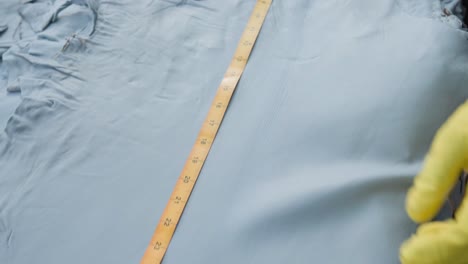 textiles worker measuring animal hides with a imperial tape measure in a leather factory