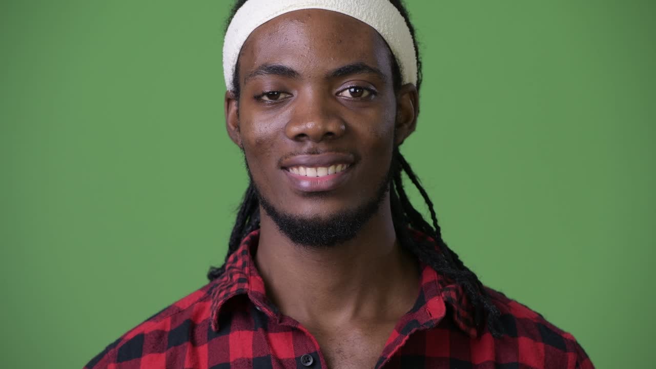 joven hombre africano guapo con dreadlocks contra un fondo verde