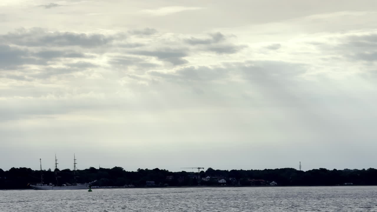 Quiet Moment on the North Sea Lone Sailboat Drifts Along the Coast, Silhouetted Against the Dramatic Sky as Storm Clouds Gather on the Horizon