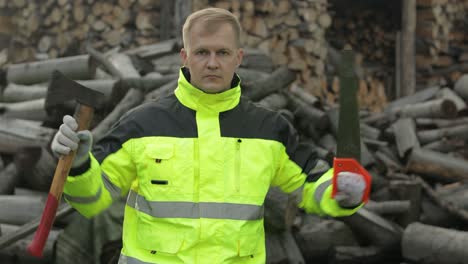 lumberjack in reflective jacket. man woodcutter holds small axe and saw on his hands. firewood