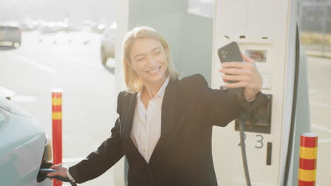 businesswoman taking a selfie at an ev charging station