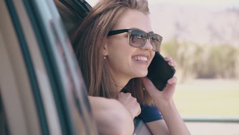 joyful-woman-talks-on-phone-looking-out-of-auto-on-nice-day