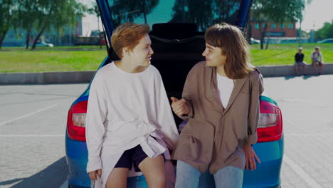 two women talking near an open car trunk