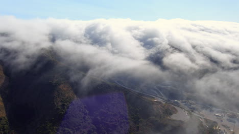 fog rolling in over the mountain landscape along the west coast in brisbane, california - dynamic aerial view