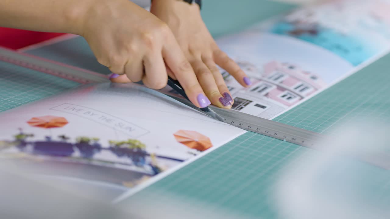 female hands cutting paper picturec useing sharp paper knife and marker at the table