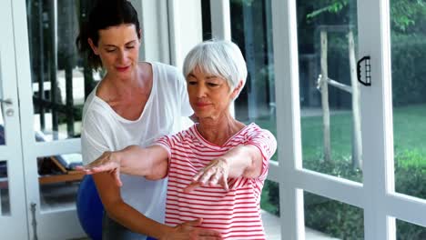 Female-coach-assisting-senior-woman-in-performing-exercise