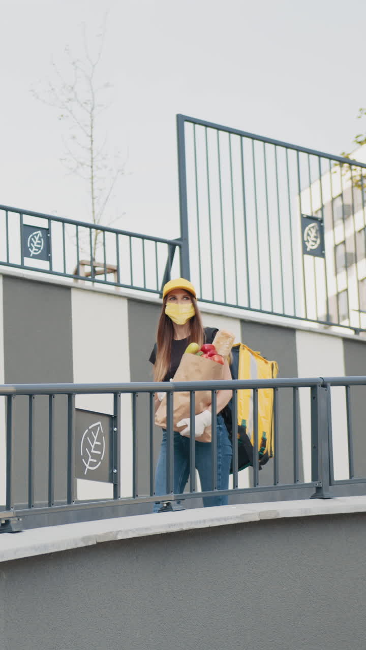 Delivery person wearing mask carrying groceries