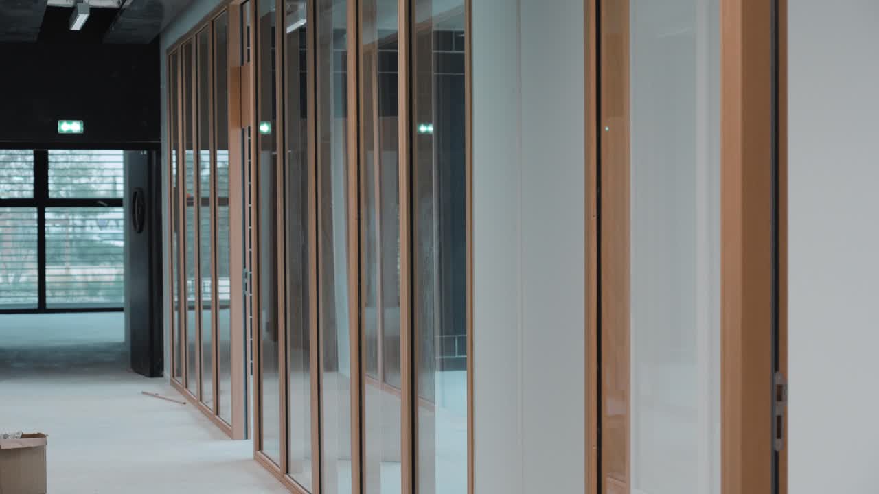 Building corridor under construction with wood-framed glass walls and minimalistic industrial design, a French commercial building.