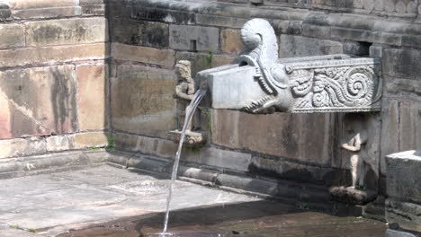 water pouring out of a stone water spout, dhunge dhara or hiti at a hindu temple at the unesco world heritage site of patan durbar marg in kathmandu, nepal