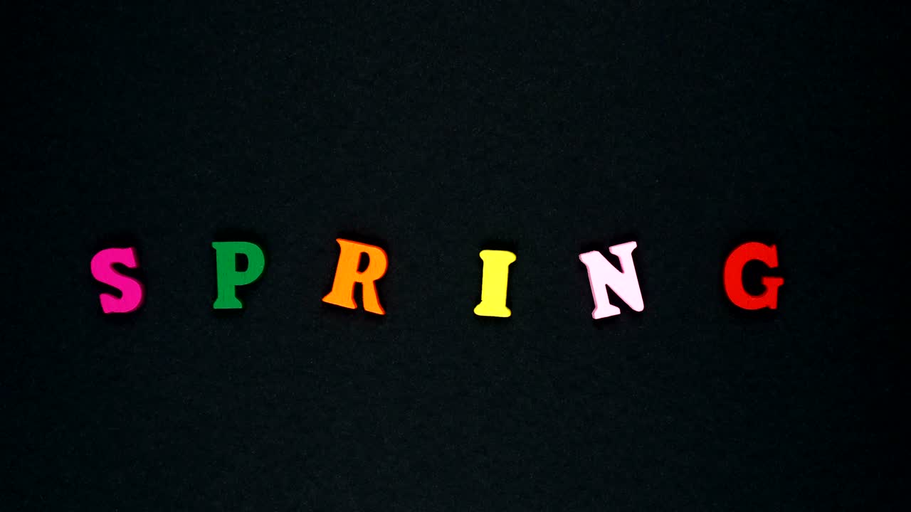 la palabra "primavera" está formada por letras de madera multicolores. las palabras coloridas son bucles.