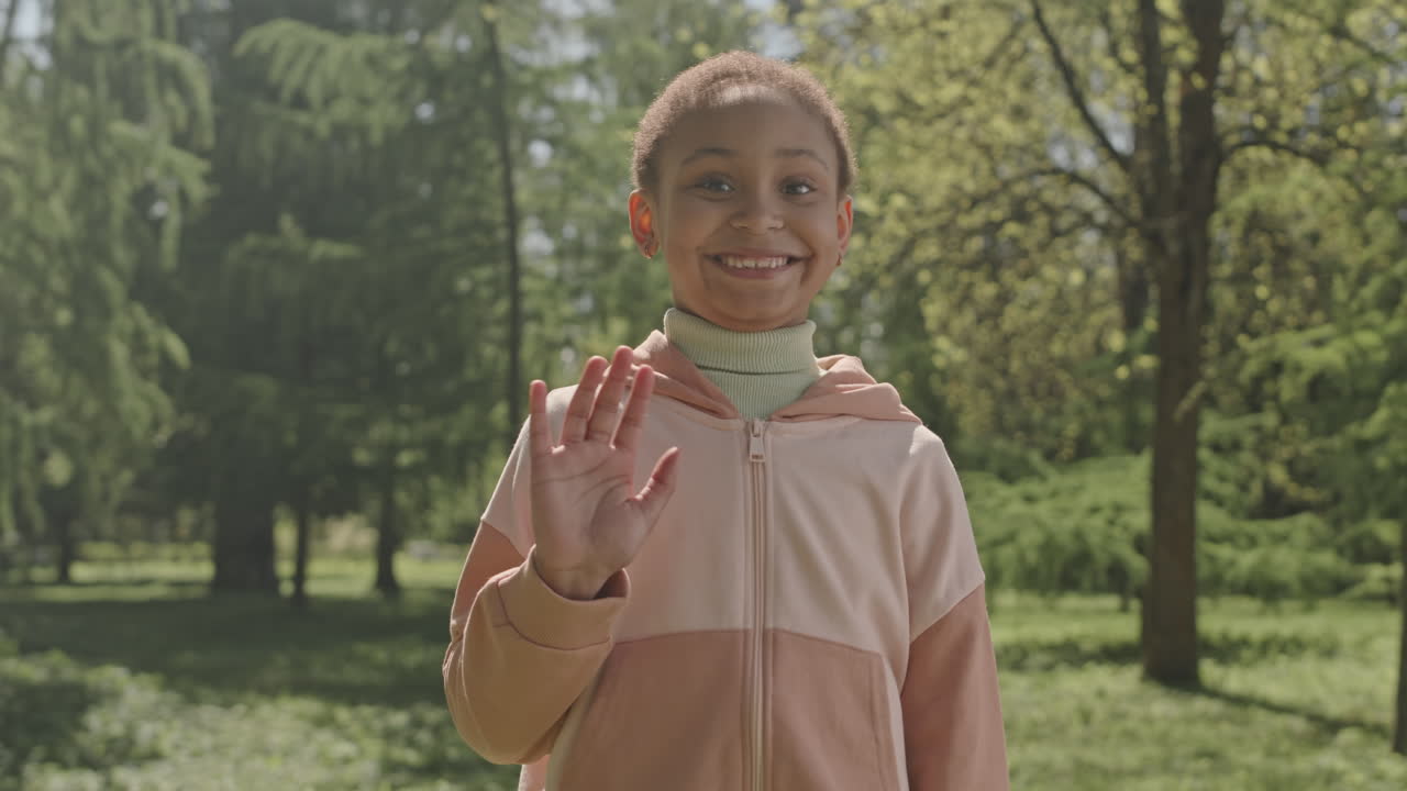 Portrait of Cute African American Girl Waving and Smiling in Park