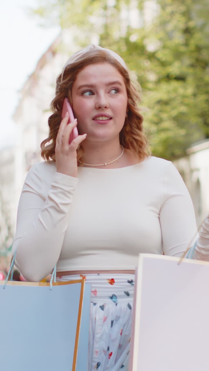 Happy woman shopaholic consumer after shopping sale with full bags with gifts talking on smartphone