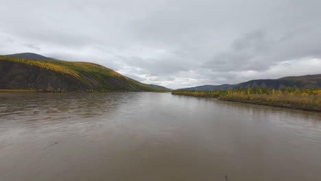 experience the tranquility of a winding river framed by majestic mountains and colorful autumn trees