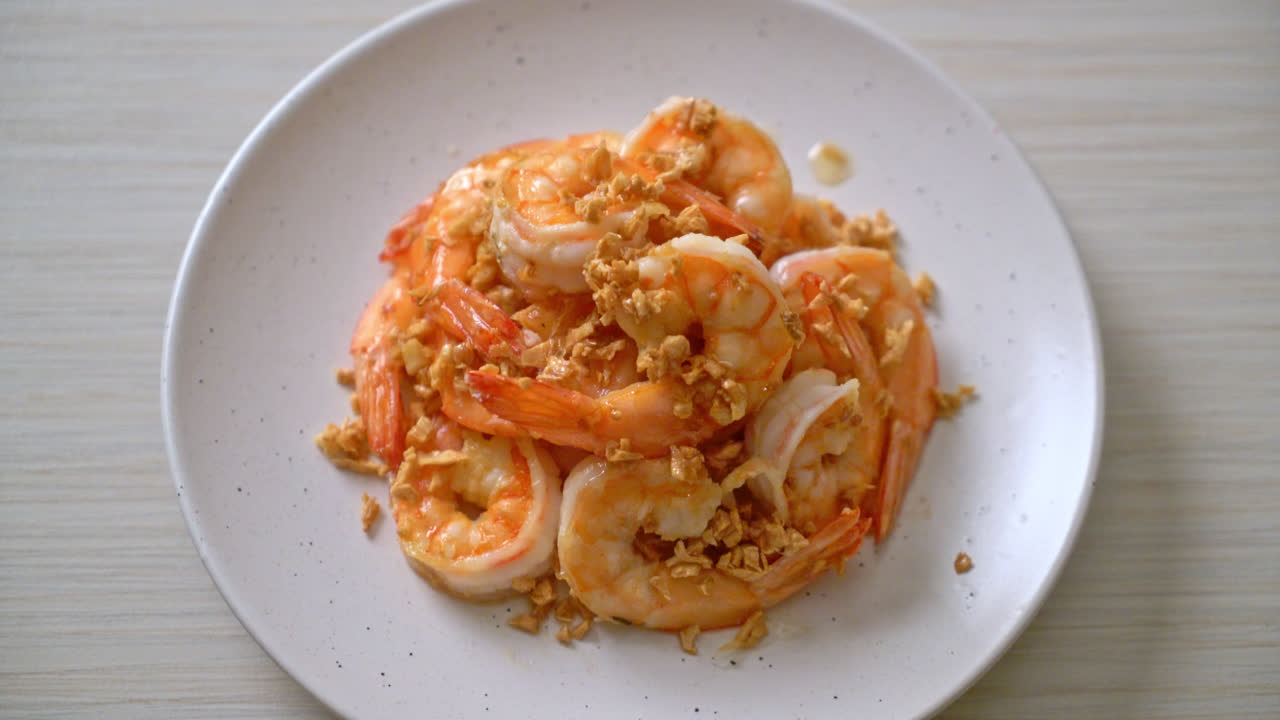 흰 접시에 마늘을 얹은 튀긴 새우 또는 새우 - 해산물 스타일