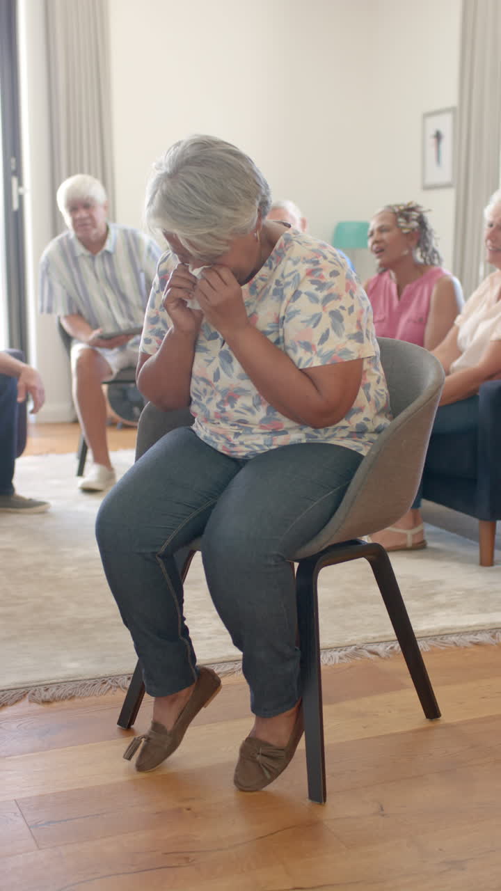 Vertical video of serious senior diverse people talking and crying during therapy in slow motion