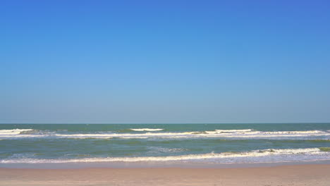 caribbean sea waves breaking on empty white sand beach on sunny summer day with endless horizon