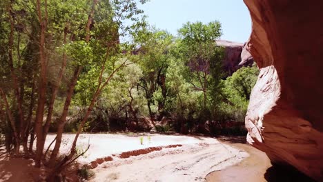 Tiro-De-Drone-Volando-Suavemente-Hacia-Atrás-Bajo-Un-Arco-De-Roca-Roja-Natural-Encontrado-En-El-Sur-De-Utah