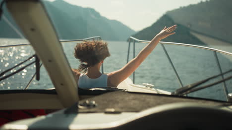 mujer se alegra de las vacaciones de verano viajando en un yate moderno empapándose del sol y observando la belleza del mar. dama mira fuera de la escotilla de la cabina estirando los brazos hacia los lados