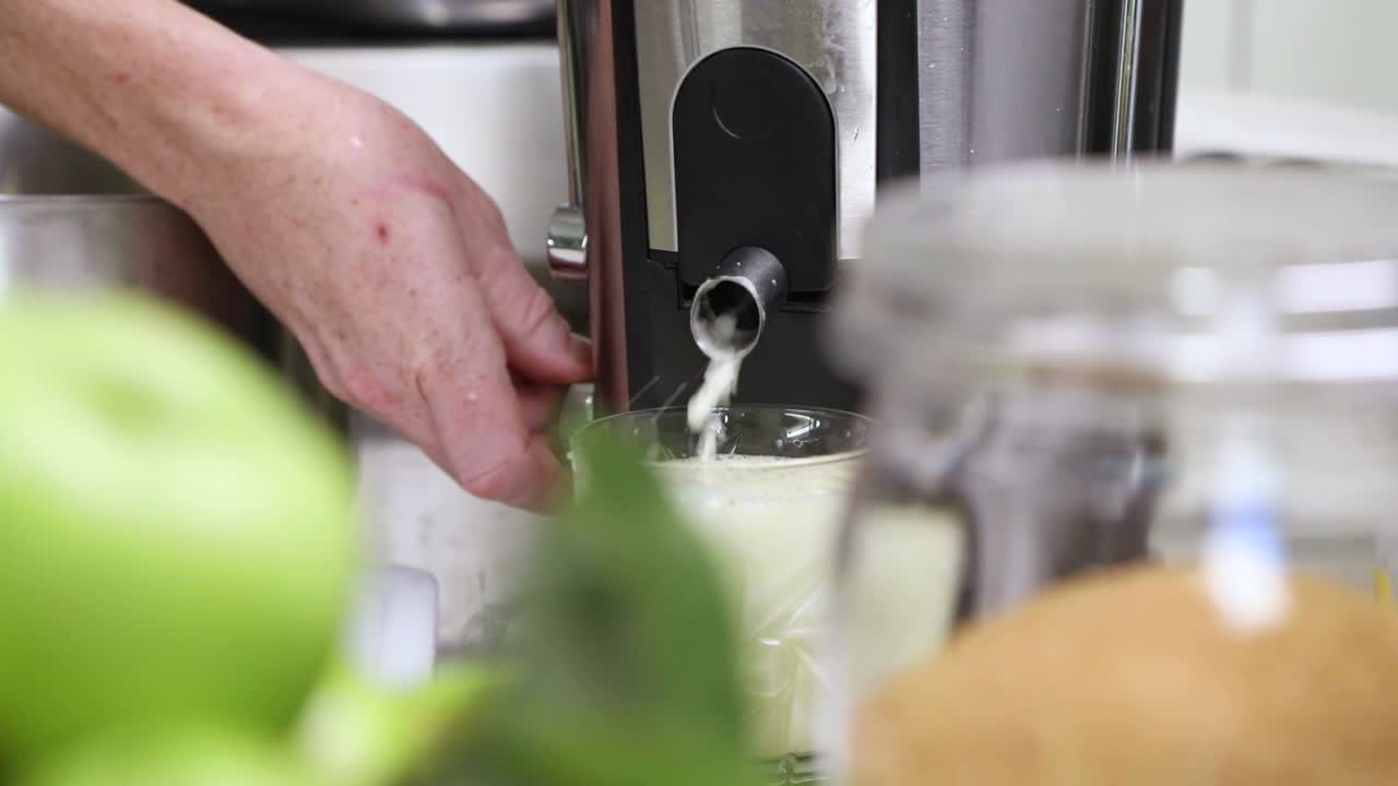 la mujer presiona la manzana en el extractor de jugo en la cocina - jugo de manzana fresco