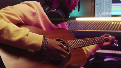 hombre afroamericano tocando la guitarra en un estudio de grabación