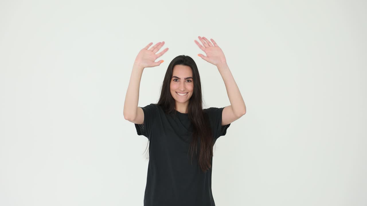 Giovane donna che sorride e saluta con le mani su sfondo bianco