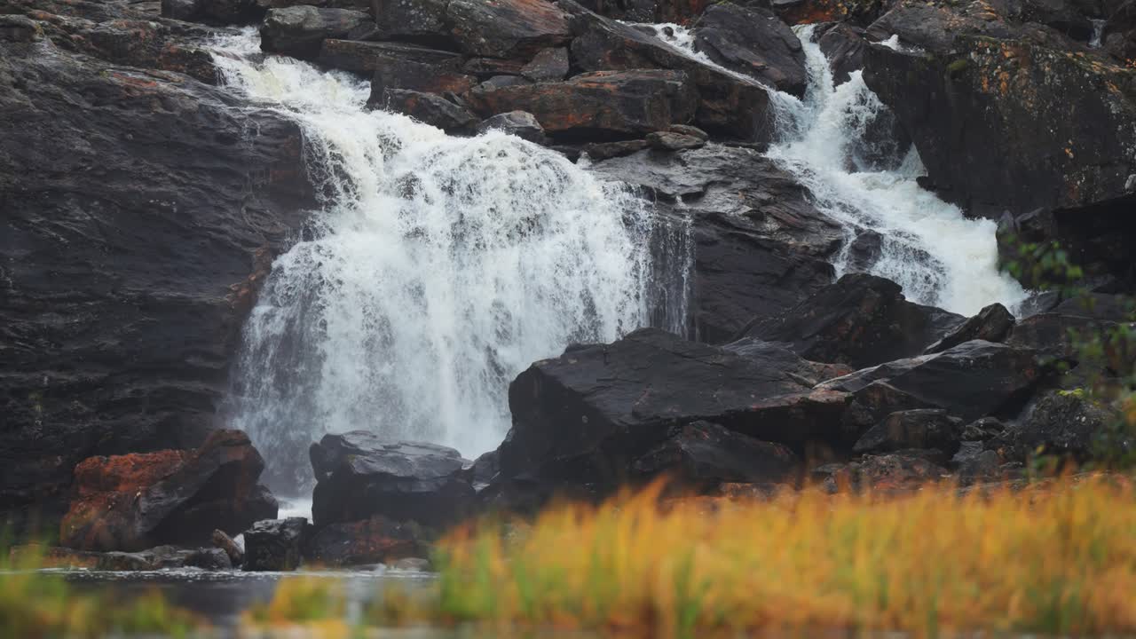 Whitewater of the mountain river rushes over the dark rocks