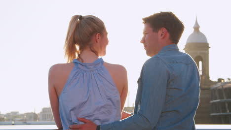 romantic couple standing on bridge over river thames in london