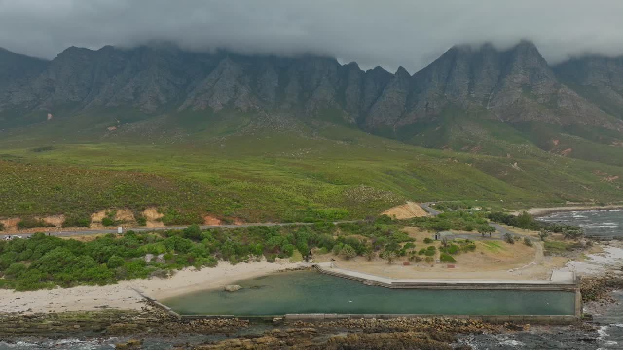 dron volando hacia una piscina de marea vacía con hermosas montañas en el fondo