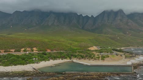 dron volando hacia una piscina de marea vacía con hermosas montañas en el fondo